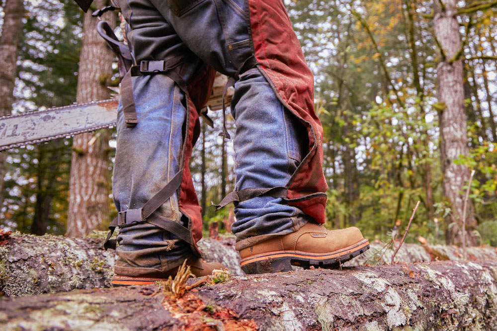 A man wearing Chippewa Super DNA work boots while standing on a log.